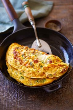 two omelets are in a black pan with a spatula on the side