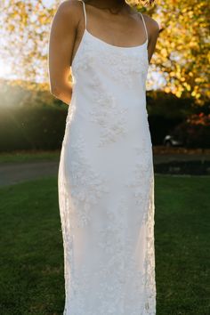 a woman wearing a white dress standing in the grass