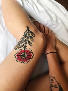 a woman laying in bed with her legs crossed and tattoos on her arms, both showing