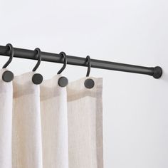 the curtain rod is holding two curtains in front of white walls and black metal rods