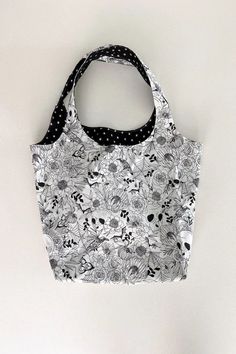 a black and white bag with skulls on it hanging from the wall next to a pair of scissors