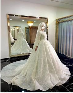 a woman in a white wedding dress looking at herself in the mirror