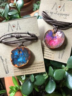 two bracelets with different designs on them sitting next to each other in front of some plants