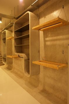 empty shelves are hanging from the ceiling in a room with concrete walls and flooring