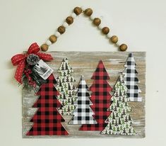 a wooden sign with christmas trees on it hanging from a string attached to a wall