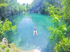 a woman floating in the middle of a river surrounded by trees