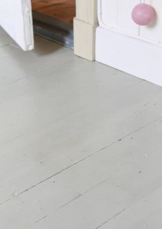 a cat is sitting on the floor in front of a white bed and pink door knobs