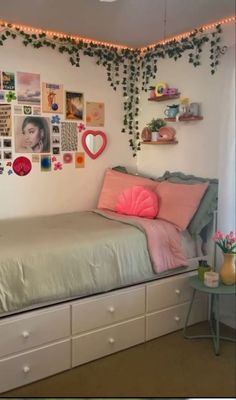 a room with a bed, dresser and pictures on the wall above it that have been decorated with plants