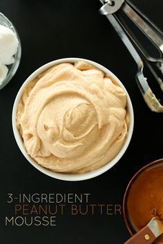 a bowl of hummus sits on a table next to utensils