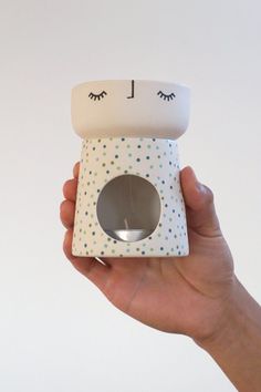 a hand holding up a small box with eyes on it's face and the lid open