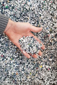 a person's hand holding something in the middle of a pile of confetti