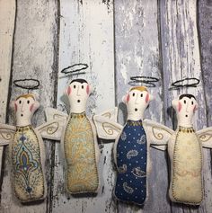 three angel ornaments hanging from hooks on a wooden wall