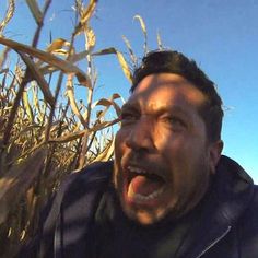 a man with his mouth open standing in a corn field