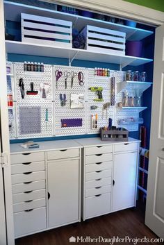 an organized craft room with white cabinets and drawers