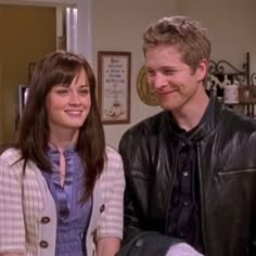 a man and woman standing next to each other in front of a kitchen counter top