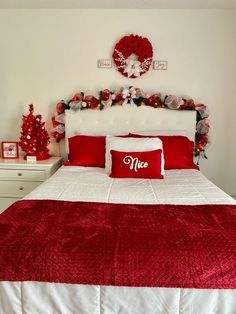 a bedroom decorated for christmas with red and white decorations on the headboard, pillows, and bed linens