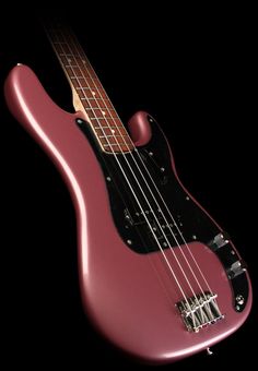 an electric bass guitar with a pink body and black neck, on a black background