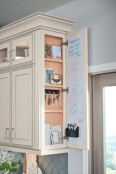 a white kitchen with lots of cupboards and drawers on the wall next to a potted plant