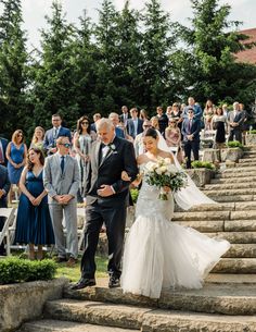 a bride and groom walking down the steps at their wedding ceremony in front of an outdoor crowd