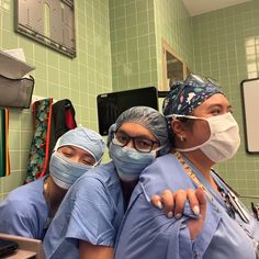 three doctors in scrubs and surgical masks are looking at the camera while standing next to each other