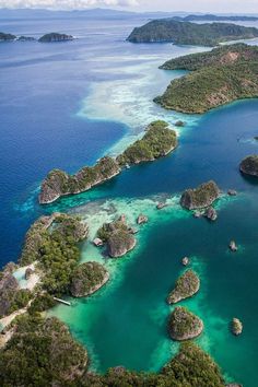 an aerial view of several small islands in the ocean with blue water and green trees