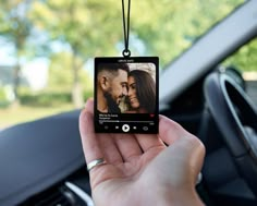 a person holding an mp3 player in their hand while sitting in the driver's seat