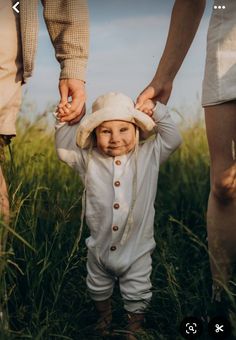 a small child is holding the hand of an adult's hand while walking through tall grass