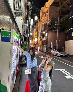 two young women standing on the side of a street