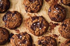 chocolate chip cookies are arranged on a sheet of parchment paper with sea salt sprinkled on top