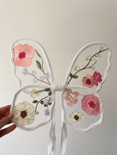 a hand is holding up a butterfly made out of paper with flowers on the wings