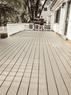 a man standing on top of a wooden deck next to a white house and trees