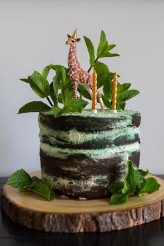 a giraffe figurine on top of a cake with leaves and greenery