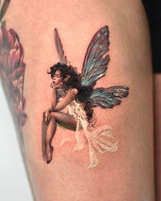 a tattoo with a fairy sitting on top of it's thigh and holding a flower