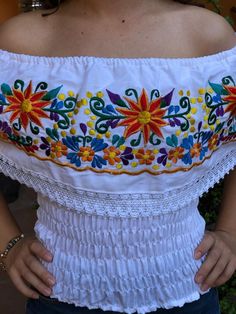 This beautiful Mexican peasant top with a spring at the waist and floral embroidery with bright colored threads will make you look spectacular. This blouse comes as a one size ideal for Small and Medium sizes. Blouse made by artisans from Oaxaca, so you can wear it on any occasion. Mexican textile art has centuries of history and creativity throughout the country. Mexico is recognized as one of the leading countries with a beautiful aristic production in the textile world, miraculous hands of ta Spring Multicolor Embroidered Peasant Top, Spring Peasant Top With Multicolor Geometric Embroidery, Bohemian Tops With Machine Embroidery, Spring Beach Peasant Top With Multicolor Embroidery, Multicolor Embroidered Peasant Top For Spring, Folk Style Peasant Top With Floral Embroidery For Beach, Peasant Floral Embroidered Top For Beach, Spring Folk Tops With Machine Embroidery, Spring Folk Style Tops With Machine Embroidery