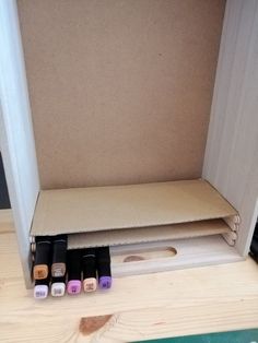 an open cardboard box with four different nail polish bottles in front of it on a wooden table