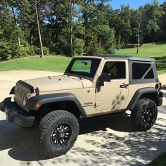 the jeep is parked on the side of the road in front of some grass and trees