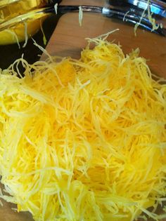 shredded cheese on a cutting board next to a glass bowl