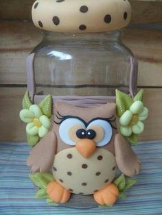 an owl figurine sitting on top of a table next to a glass jar