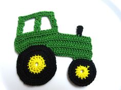 a crocheted green and black toy truck on a white surface with yellow wheels