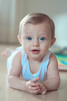 a baby with blue eyes laying on the floor