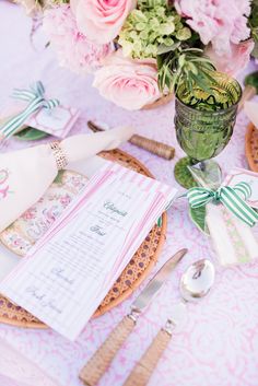 the table is set with pink flowers and place settings