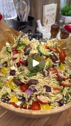 a wooden bowl filled with lots of different types of food on top of a table