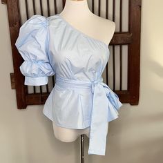 Blogger’s Favorite Top! Brand New Without Tags - Size Large Light Blue In Color Self Tie Belt So Flattering And Beautiful Measurements Are: Lbust:43.75", Waist Size:47", Length:24", Sleeve Length:13.75", Bicep Length:16", Cuff:12", Belt Length:50 Color Of Top On Model Is More Purple Than What I Own. Smoke And Pet Free Home Blue Fitted One-shoulder Top, Blue One-shoulder Blouse, Chic Blue One-shoulder Blouse, Blue One-shoulder Top For Day Out, Light Blue Fitted Puff Sleeve Blouse, Shoulder Puff Sleeve, Tan T Shirt, Oversized Tee Shirt, Cropped Graphic Tees