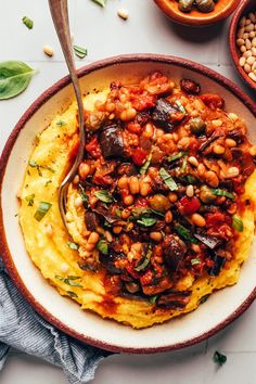 a white plate topped with polenta and beans next to bowls of beans, herbs and seasonings