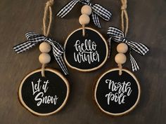 three black and white wood slice ornaments hanging from twine with words written on them