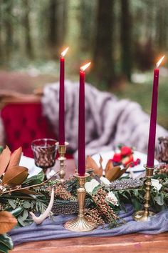 candles are lit on a table in the woods