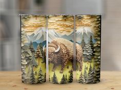 three tall vases with an image of a bison in the woods on them, sitting on a table