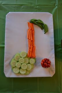 carrots, cucumbers and green beans are arranged on a white cutting board