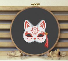 a cross stitch cat with a red tassel on it's head and eyes