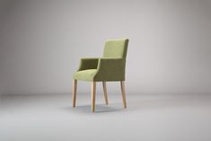 a green chair sitting on top of a white floor next to a gray wall in an empty room